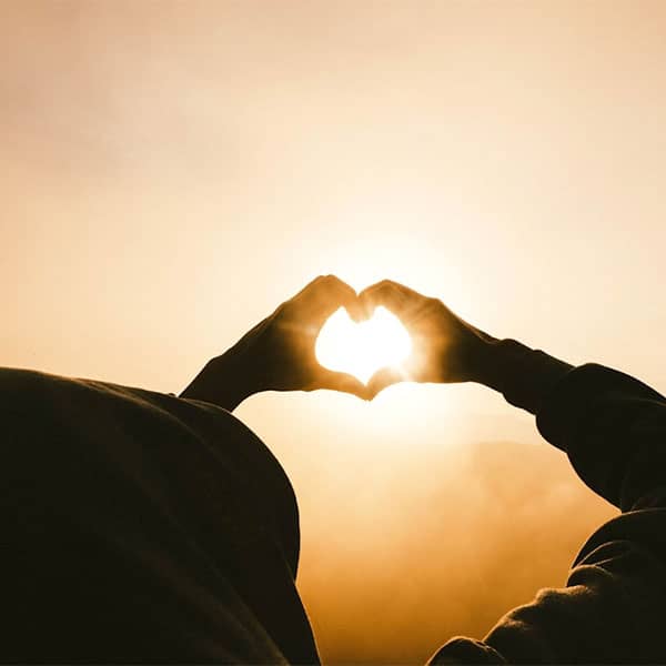 Holding up heart sign to the sun